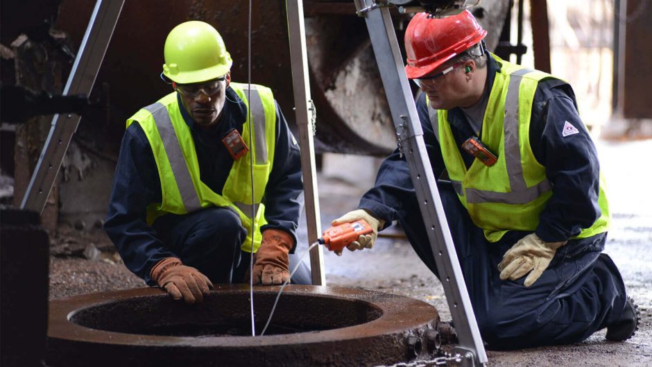 Trabalhadores utilizando EPIs se preparando para entrar em espaço confinado