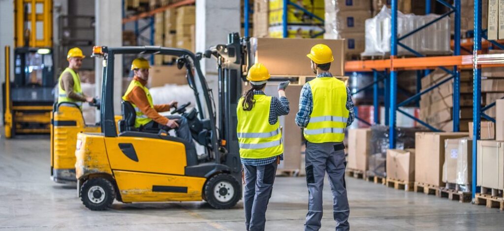 Trabalhador pilotando empilhadeira em galpão de estoque