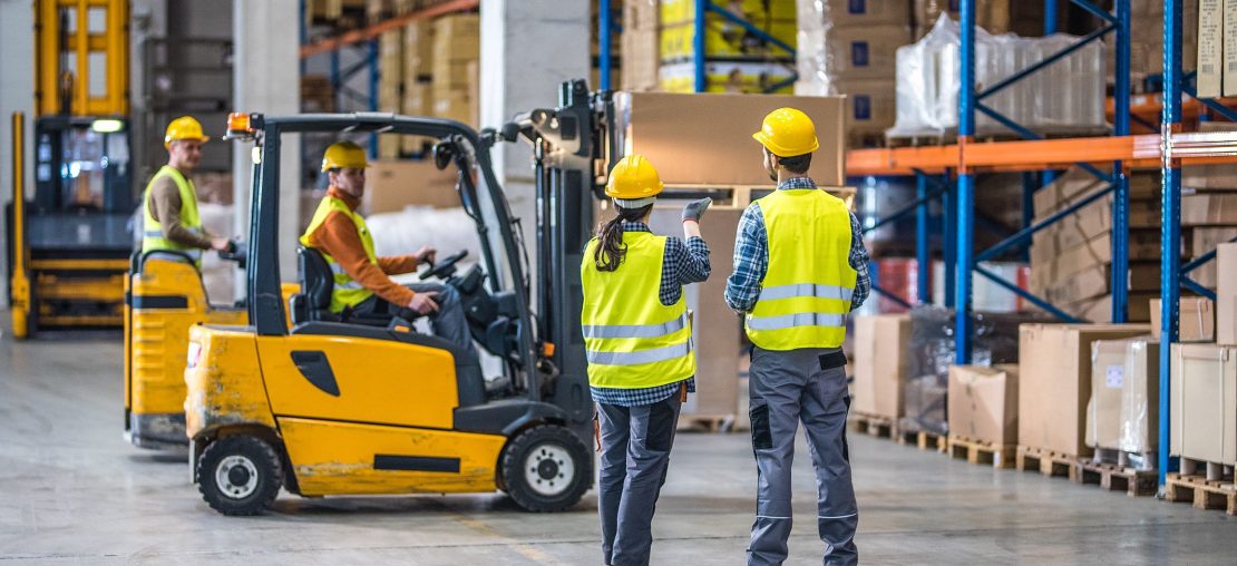 Trabalhador pilotando empilhadeira em galpão de estoque